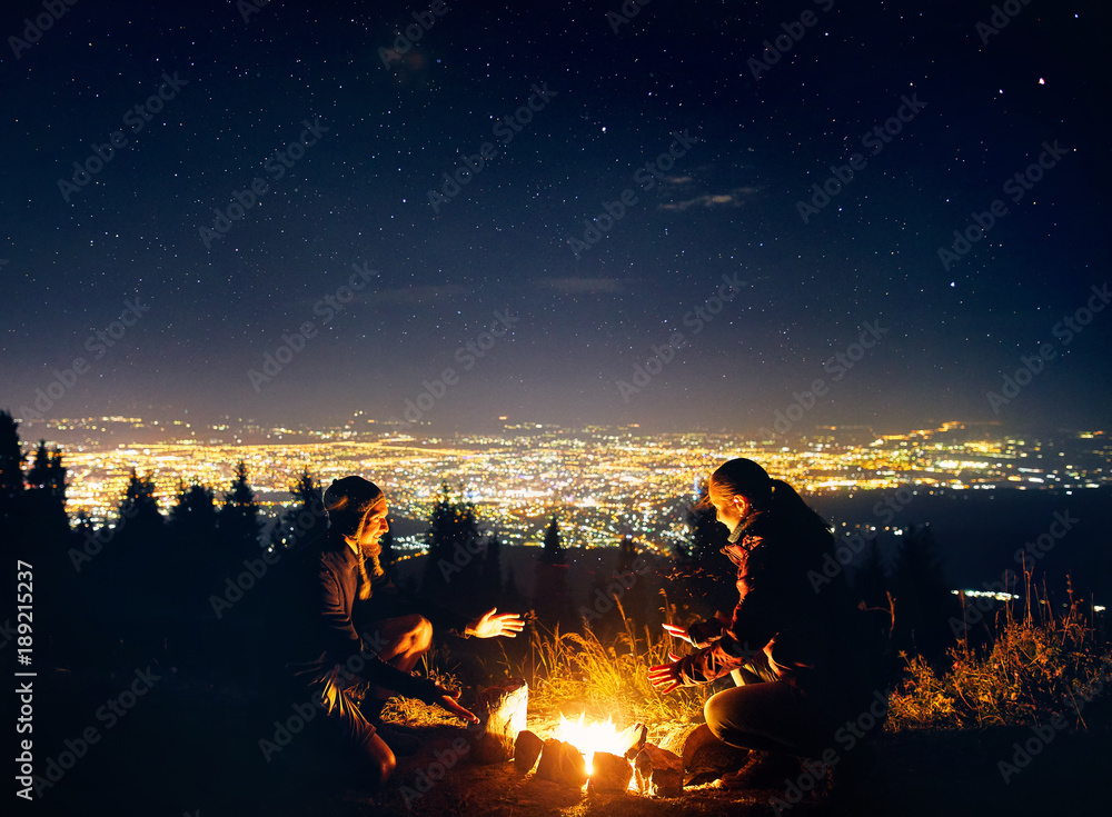 Romantic couple near campfire at starry night - obrazy, fototapety, plakaty 