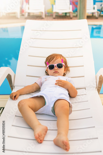 Cute baby relaxing at sunbed near pool at hawaii, hotel