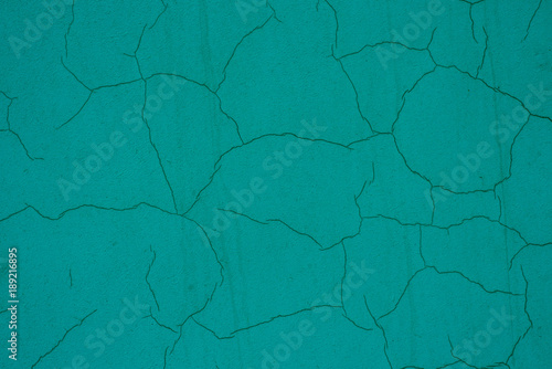 Old green plaster with cracks on a concrete wall - abstract background