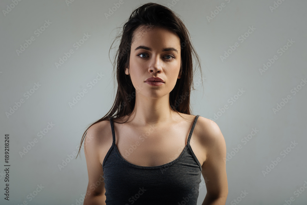 Model. Good-looking serious dark-haired young woman having deep eyes and long hair and staring and wearing a shirt Model. Good-looking serious dark-haired young woman having deep eyes and long hair and staring and wearing a shirt