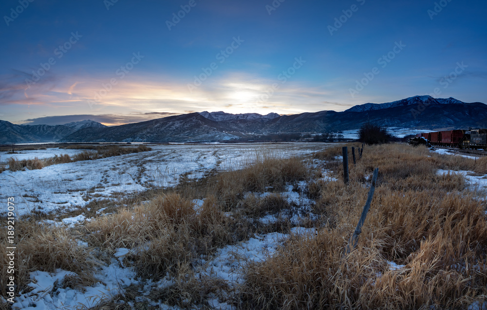 Sunset winter landscape of a rural area with train cars in the snowy tracks Sunset winter landscape of a rural area with train cars in the snowy tracks