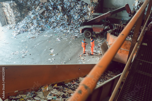 Workers standing at conveyor in recycling facility