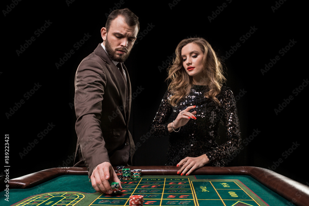 Man and woman playing at roulette table in casino Man and woman playing at roulette table in casino