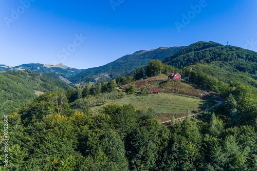 The house on a mountain of red color is surrounded by green trees. aerial view.