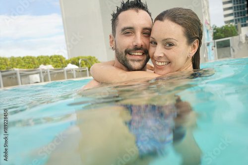 Cheerful couple enjoying bath in resort swimming pool