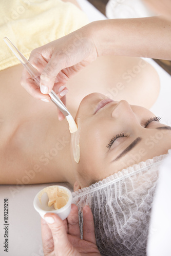 Obraz na płótnie The client is lying peacefully waiting for the beautician to put on her face mask w salonie