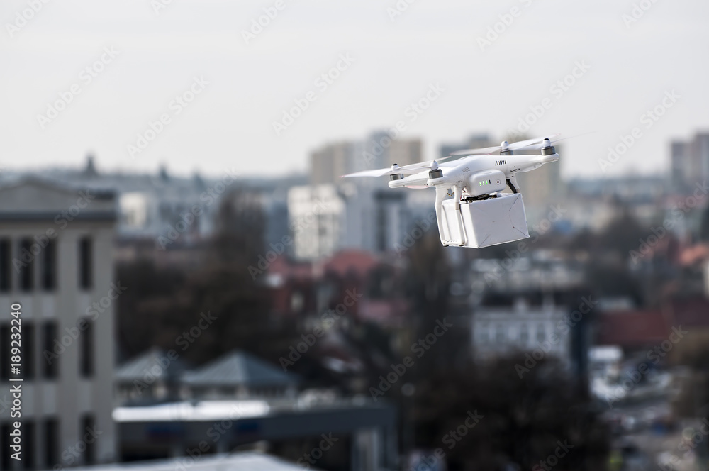 Technological delivery innovation - fast drone delivery concept above town Technological delivery innovation - fast drone delivery concept above town