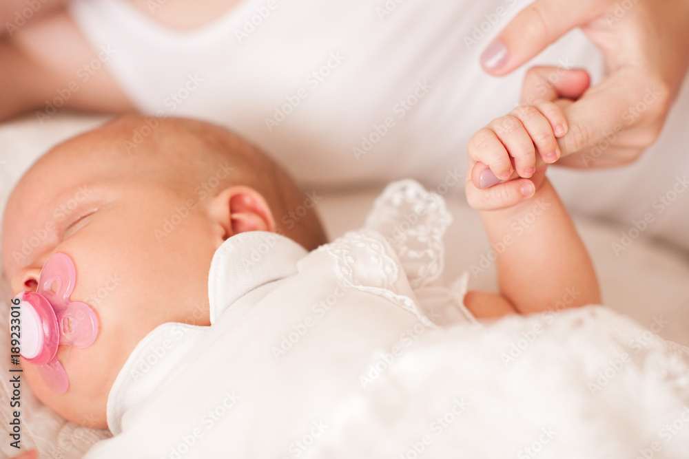 Mother holding baby fingers lying in bed close up. Mother holding baby fingers lying in bed close up.