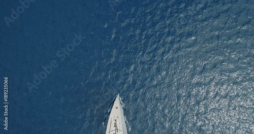 Perpendicular aerial view of a sailing boat navigating slowly.