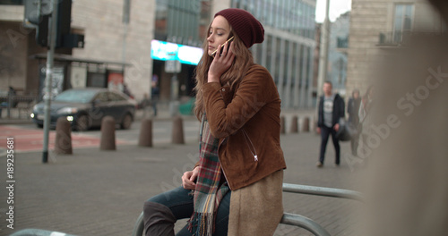 Beautiful brunette talking on phone in a city.