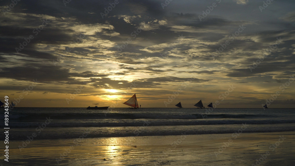 Sunset over the sea in the background boats,sailing boat, orange sky and islands. Sailing boats at sunset in the sea. Travel concept. Beautiful serene scene. Philippines, Boracay. Travel concept. Sunset over the sea in the background boats,sailing boat, orange sky and islands. Sailing boats at sunset in the sea. Travel concept. Beautiful serene scene. Philippines, Boracay. Travel concept.