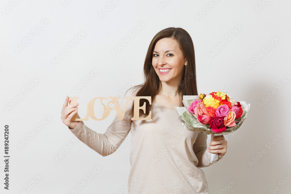 Young smiling woman holding wooden word Love, bouquet of beautiful roses flowers isolated on white background. Copy space for advertisement. St. Valentine's Day or International Women's Day concept. Young smiling woman holding wooden word Love, bouquet of beautiful roses flowers isolated on white background. Copy space for advertisement. St. Valentine's Day or International Women's Day concept.