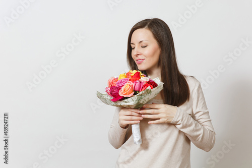 Young smiling woman sniffing and holding bouquet of beautiful roses flowers isolated on white background. Copy space for advertisement. St. Valentine's Day or International Women's Day concept.