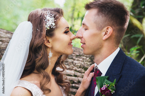 Beautiful newlywed bride and groom hugging in park.