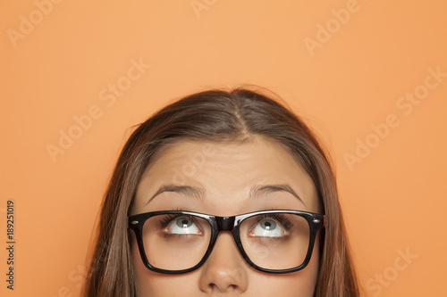 half portrait of a young girl with glasses looking up
