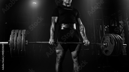 Professional athlete is standing and is holding a very heavy barbell. photo