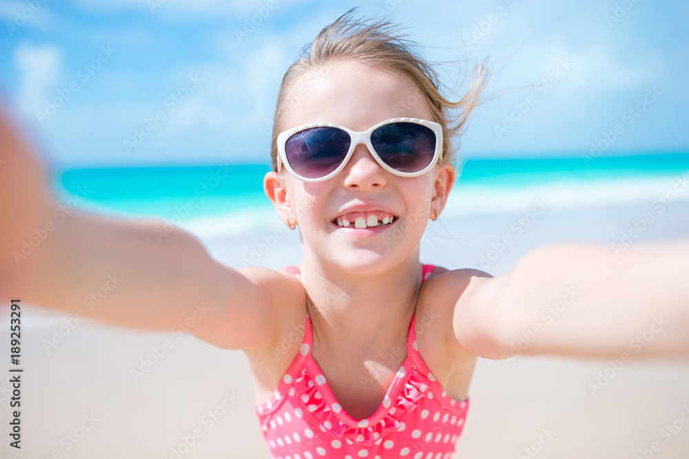 Happy little girl taking selfie at tropical beach on exotic island Happy little girl taking selfie at tropical beach on exotic island