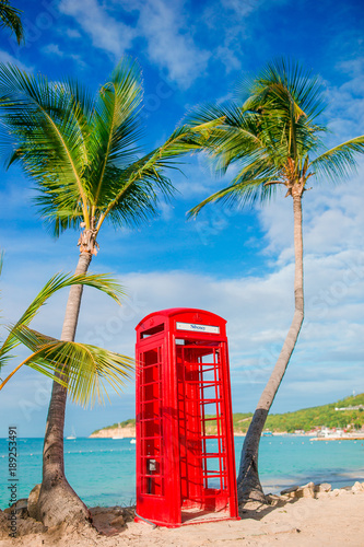 Red phone booth in Dickenson's bay Antigua. Beautiful landscape with a classic phone booth on the white sandy beach in Antigua photo