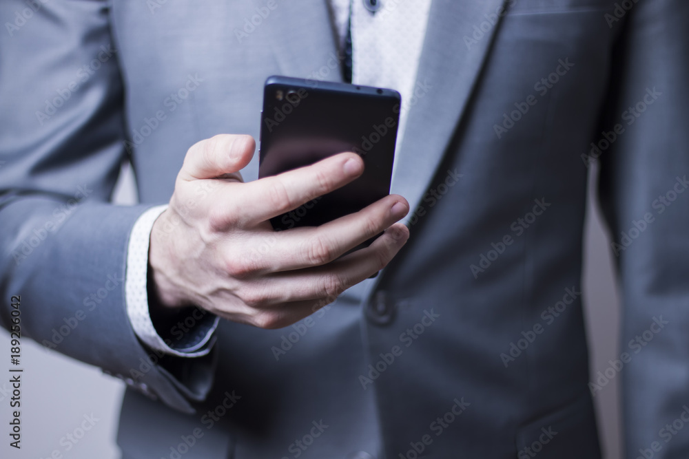 Closeup of sharp looking businessman in grey suit holding mobile phone. Closeup of sharp looking businessman in grey suit holding mobile phone.
