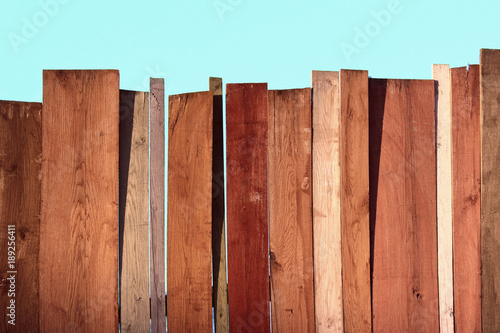 Multicolored wooden wall and blue sky. A colored wall of wood with a lot of copy space. Wooden fence and blue sky. Colored Painted Old Shabby Wooden Desk Background. Wooden Background.
