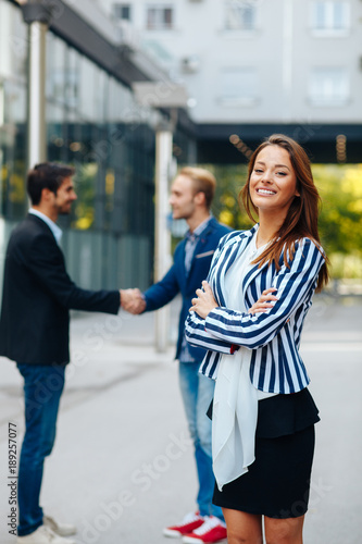 Young businesswoman posing in front of two man shaking hands © djile