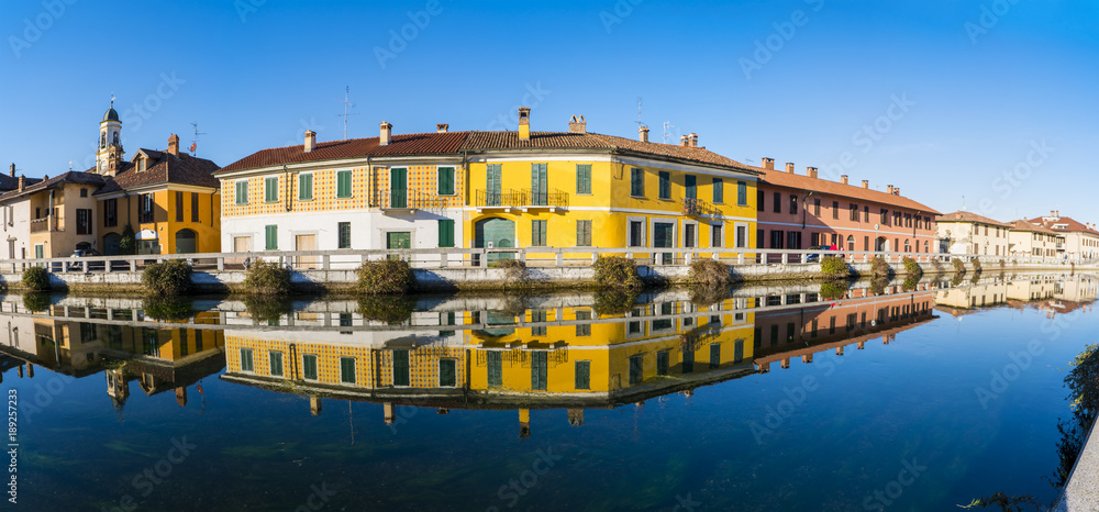 Cityscape of Gaggiano (Milan, Italy); colorful houses reflected in the Naviglio Grande canal waterway