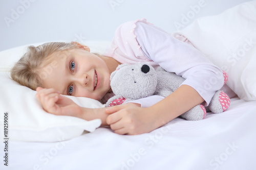 Child little girl sleeps in the bed with a toy teddy bear