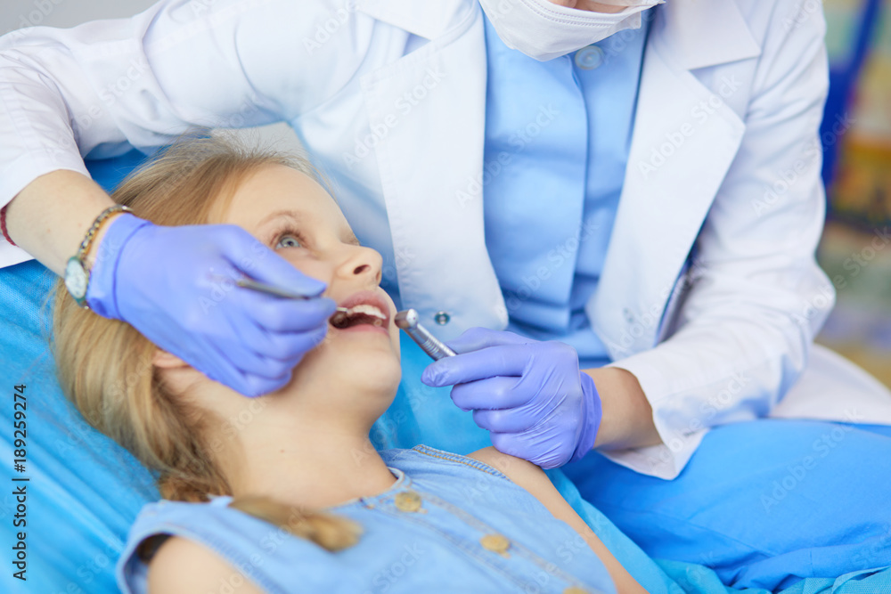 Naklejka premium Little girl sitting in the dentists office