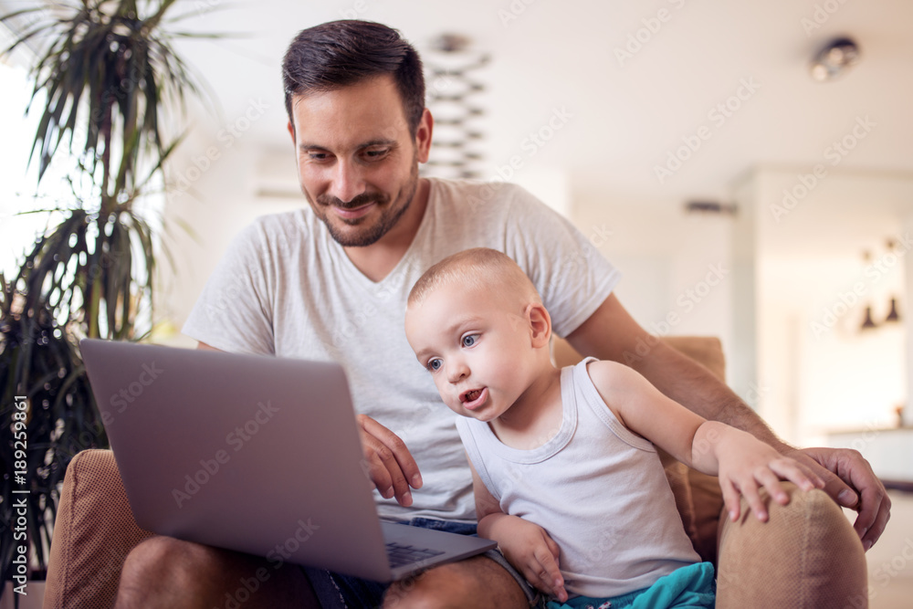 Father and son looking at laptop and smiling. Father and son looking at laptop and smiling.