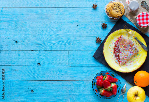 Fresh homemade crepes served on a plate with strawberries and blueberries, on a light blue wooden background, free space for text.