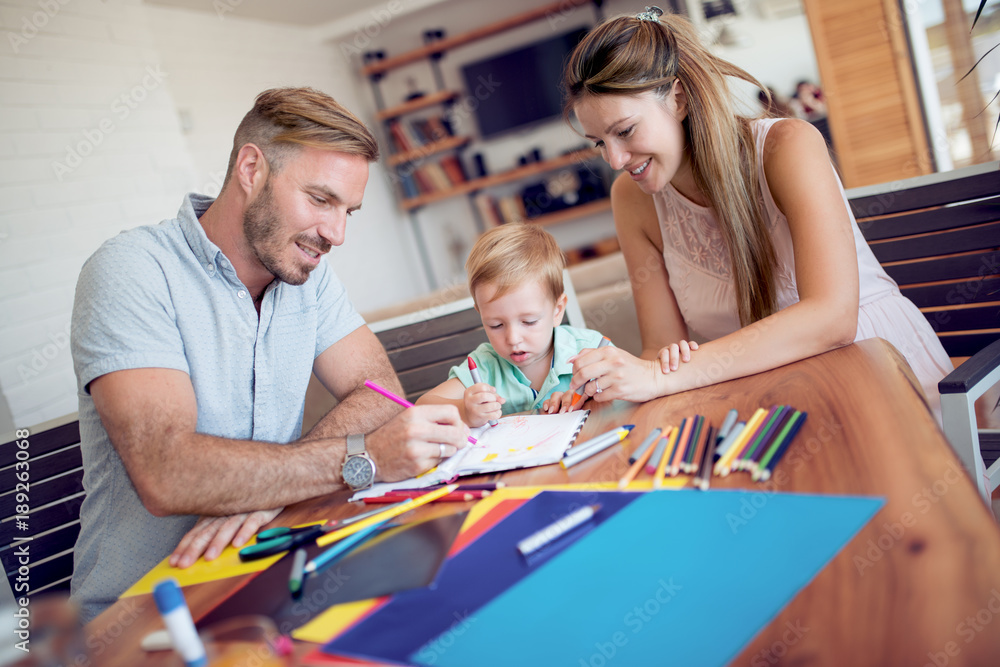 Fototapeta premium Smiling family drawing together in kitchen at home