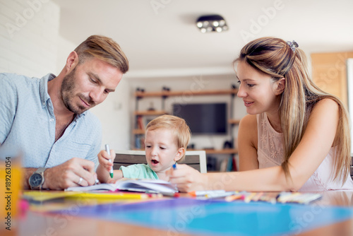 Smiling family drawing together in kitchen at home