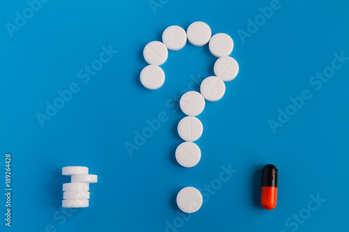 The tablets are white meds on a blue background. A symbol of a question mark. Choose between multiple pills and medical pills