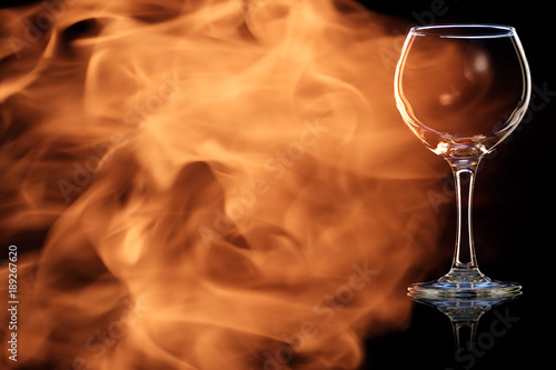 An empty glass of red wine in the fire flames.