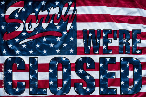 government shutdown represented by a sorry we're closed sign outline with american flag background