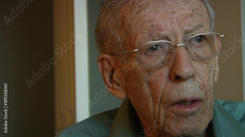 Elderly man watching TV looks down to change channel photo