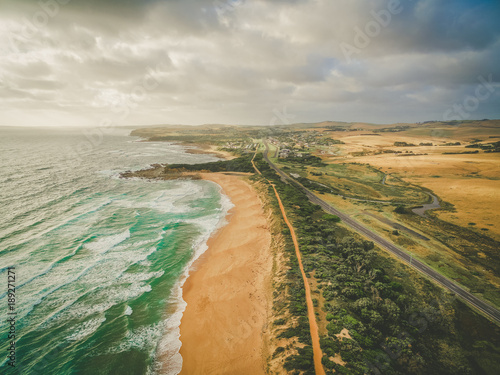 Rural highway passing near beautiful ocean coastline and walking trail in Australia - aerial landscape