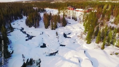 Aerial drone video of Kvikkjokk, Kamajokk, Fjällstationen. View of the stream and the hotel revealing the beautiful landscape and mountains in the distance. photo