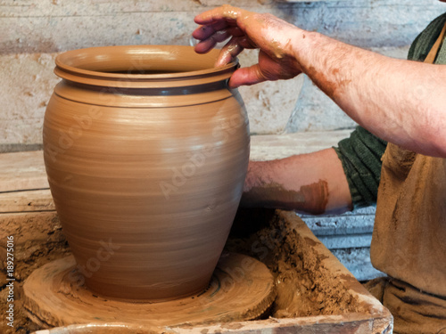 Hands of a Potter making a large vessel on the pottery wheel.