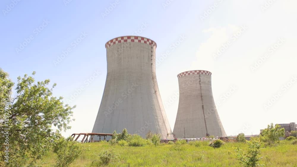 Huge cooling towers of brown coal power plant at background of industrial landscape. Nuclear power plant on the sky background in sunlight. Two cooling towers in a field in the bright sun. Industry. Huge cooling towers of brown coal power plant at background of industrial landscape. Nuclear power plant on the sky background in sunlight. Two cooling towers in a field in the bright sun. Industry.