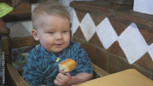 baby boy eats bread in a restaurant photo