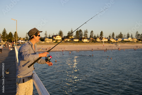 Wallpaper Mural young attractive and happy man in shirt and hat fishing at beach sea dock using fish road enjoying weekend hobby in holidays Torontodigital.ca