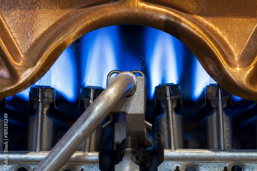 The fire burns in the modern water heater without cover. Closeup, selective focus