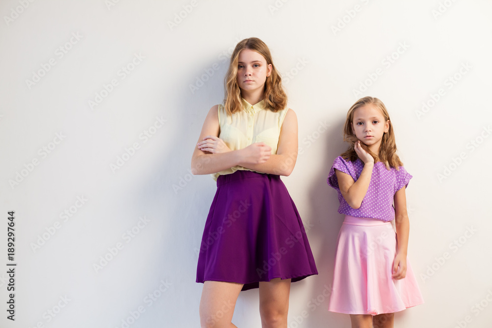 two girls sisters in colored dresses posing two girls sisters in colored dresses posing