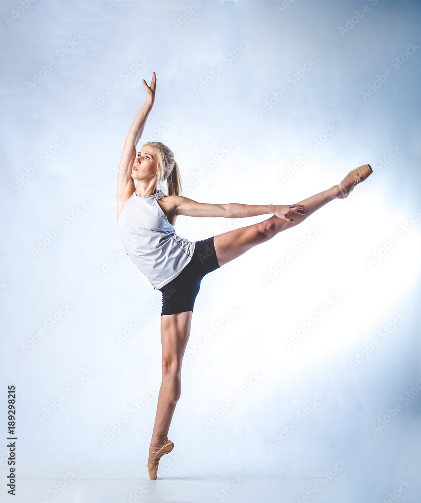 Beautiful female fitness model doing stretches and dancing in a studio, isolated against white background Beautiful female fitness model doing stretches and dancing in a studio, isolated against white background