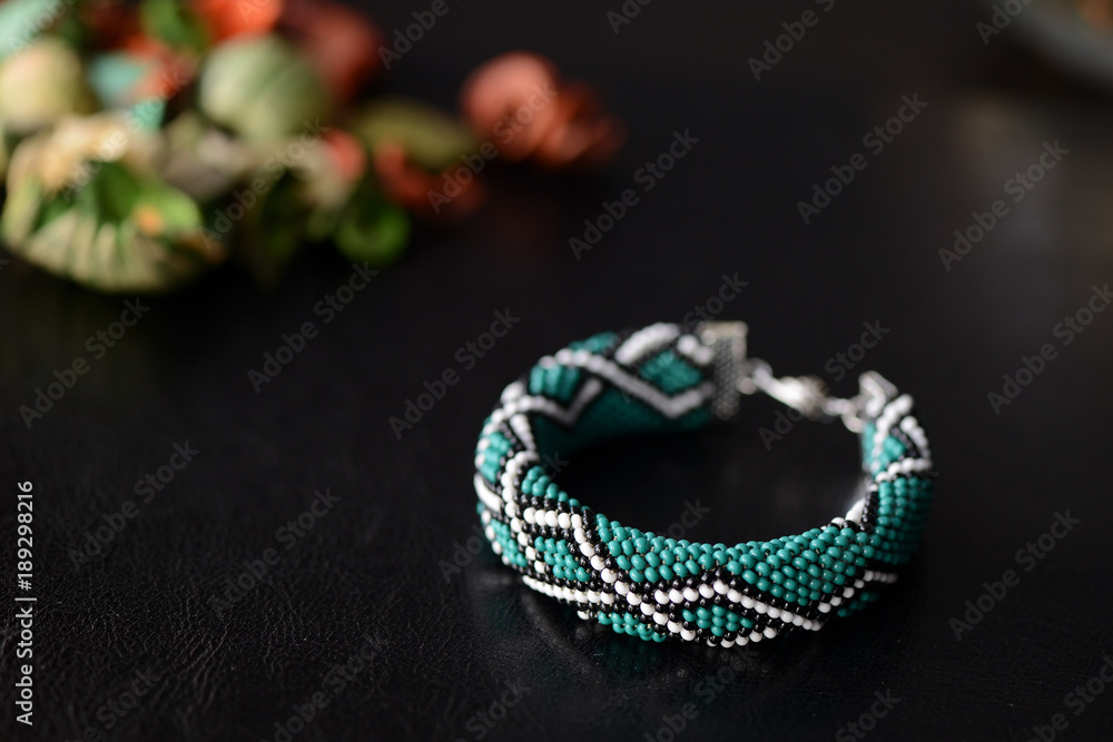 Fototapeta premium Green bead crochet bracelet with celtic print on a dark background close up