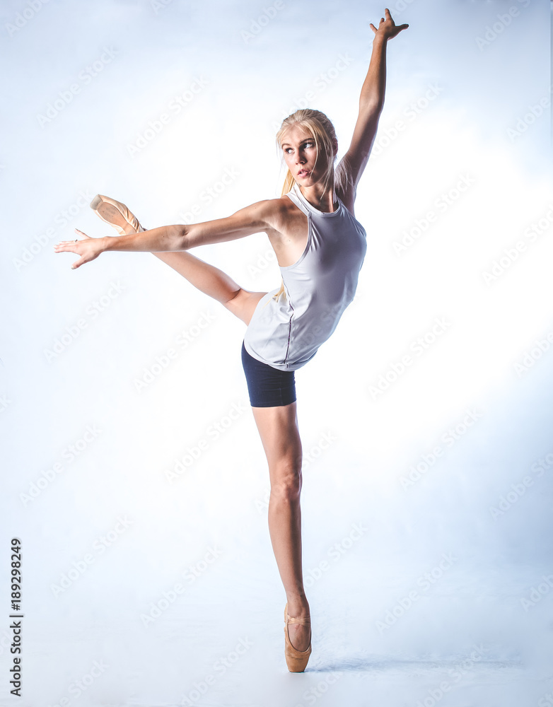 Obraz premium Beautiful female fitness model doing stretches and dancing in a studio, isolated against white background