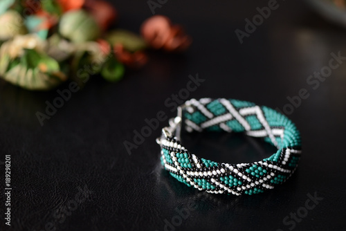 Green bead crochet bracelet with celtic print on a dark background close up