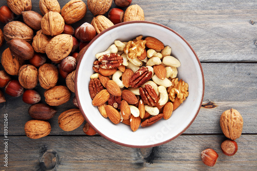 bowl with mixed nuts on wooden background. Healthy food and snack. Walnut, pecan, almonds, hazelnuts and cashews.