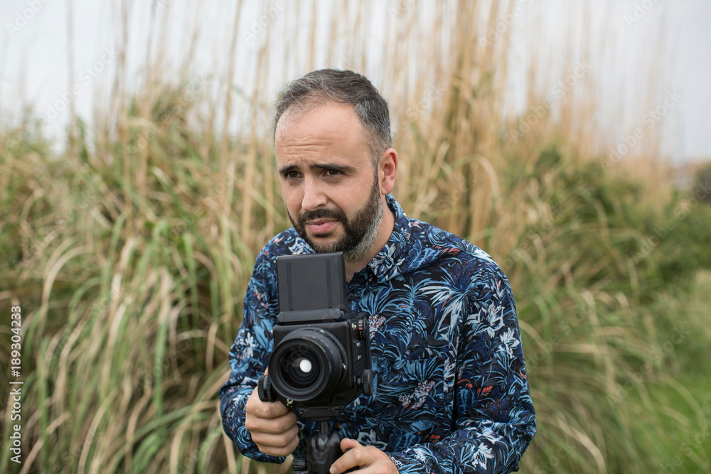 Cheerful adult man with retro camera